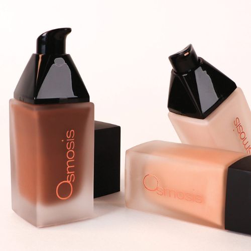 three bottles of osmosis flawless foundation in various skin colors displayed on a white background