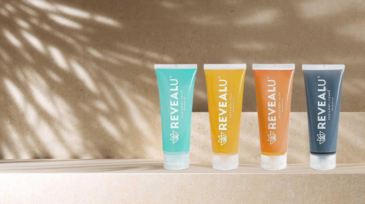 4 tubes of REVEALU skincare products displayed in a row outside