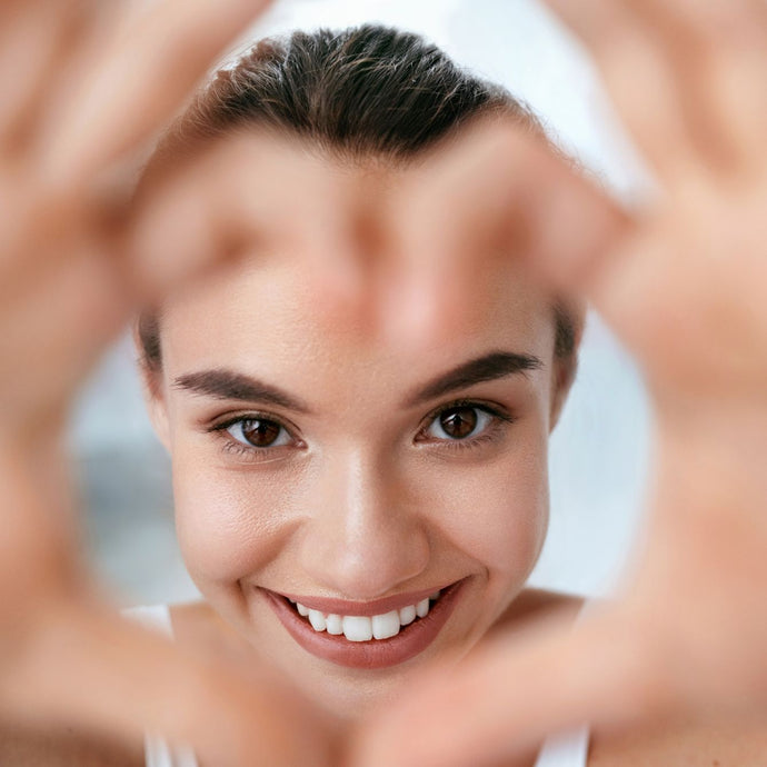 sunlighten model smiling with hands making a heart shape in front of her face