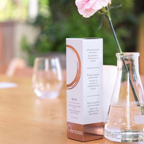 Box of Osmosis boost mist displayed on table with glasses and flowers