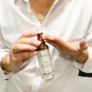 Model in white dress shirt pumping calm serum by osmosis into her hand before applying