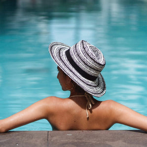 Model with a sun hat on is relaxing in a pool