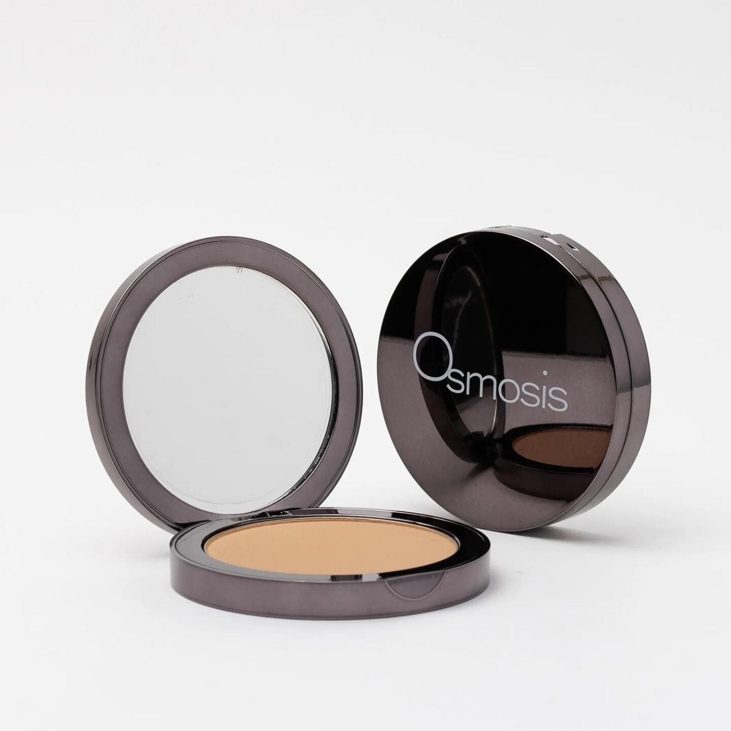 opened compact next to closed compact of pressed base powder on white background 