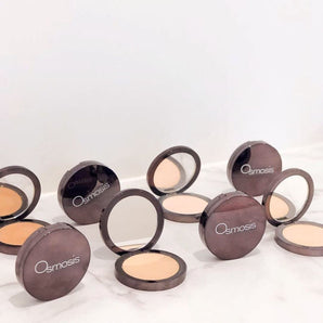 multiple opened mineral pressed base powder in a row on white background