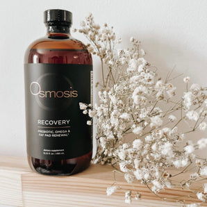 bottle of liquid recovery displayed on shelf with babies breath flowers