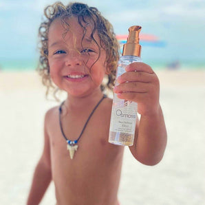 beach kid holding a bottle of sun defense elixir on a beach
