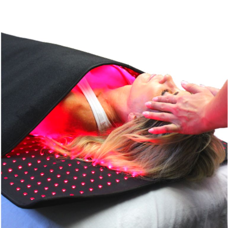client laying on full body prism infrared light pad on a treatment bed