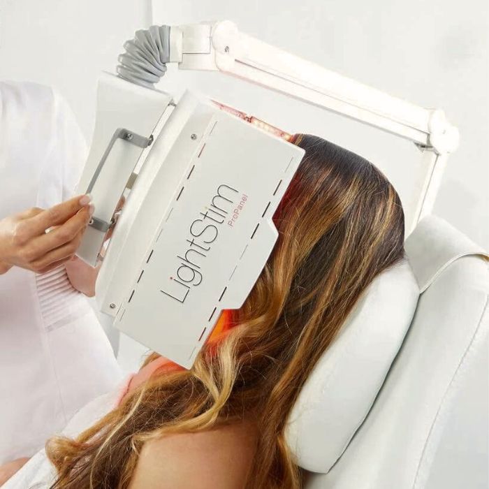 a client in a white towel laying in a salon treatment bed with a lighstim pro panel covering her face