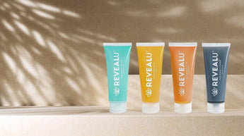 4 tubes of REVEALU skincare products displayed in a row outside 